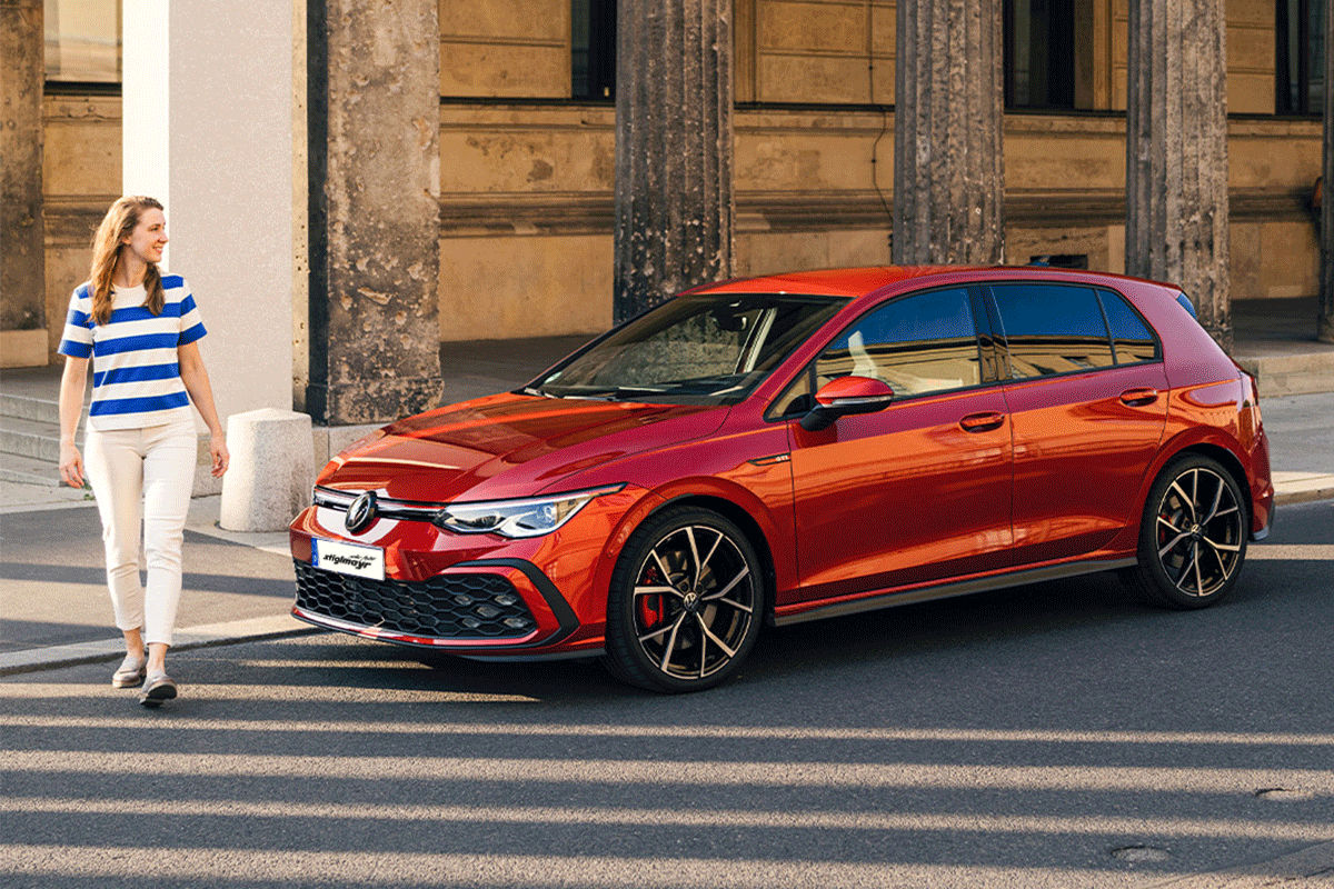 Frau neben rotem Golf GTI