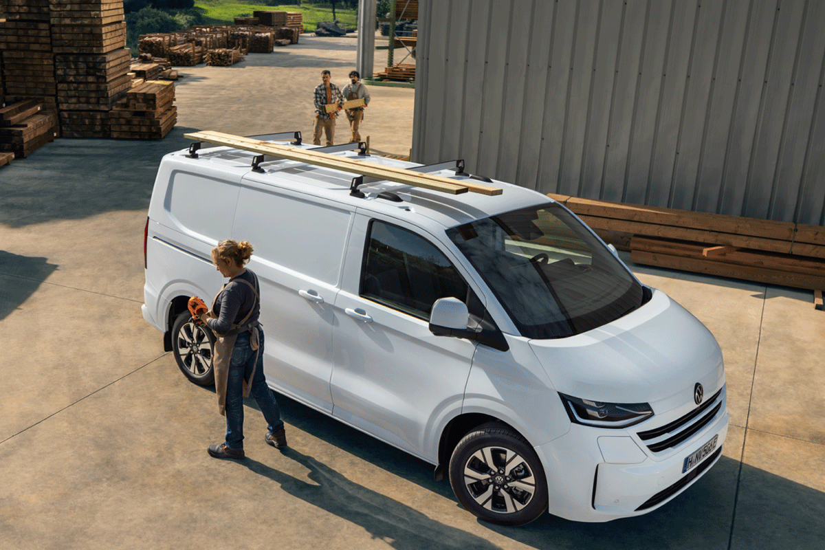 Bild zeigt eine Frau vor einem Volkswagen e-Transporter mit Holzbrettern auf dem Dach