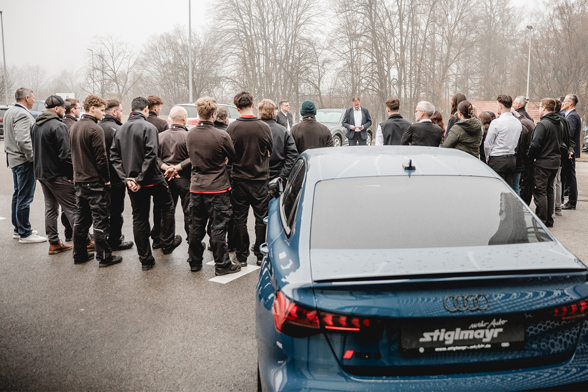 Gruppenbild der Auszeichnungsübergabe vor dem Audi Terminal mit einem Auto von hinten