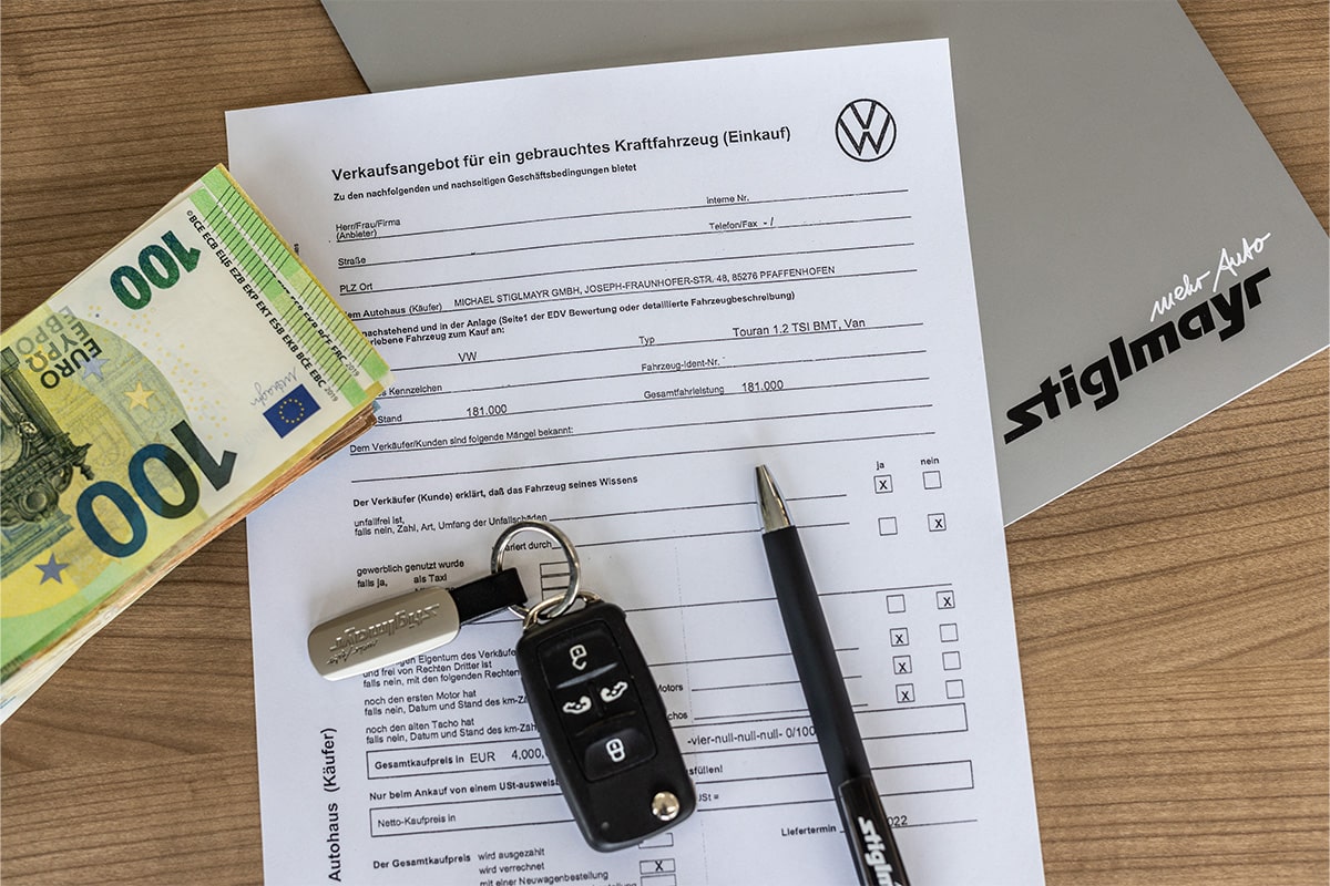 Der Vertrag zum Kaufpreisschutz liegt auf einem Tisch. Daneben liegt ein Schlüssel, Geld und ein Kugelschreiber.