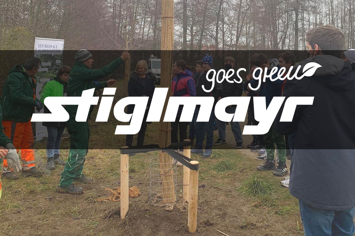 Bild zeigt das Logo Stiglmayr goes green mit einer Versammlung an Menschen im Hintergrund.