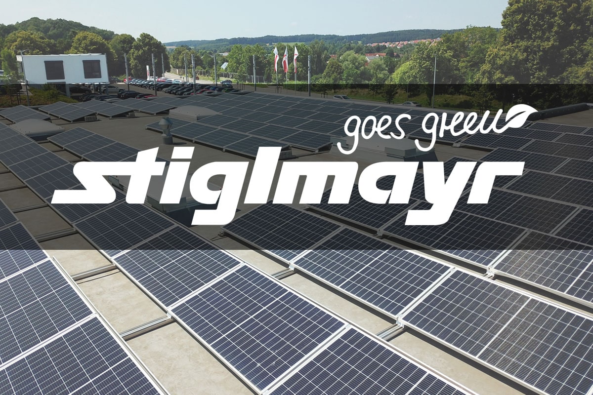 Bild zeigt das Logo Stiglmayr goes green, mit den Solaranlagen auf dem Dach des Audi Terminals.