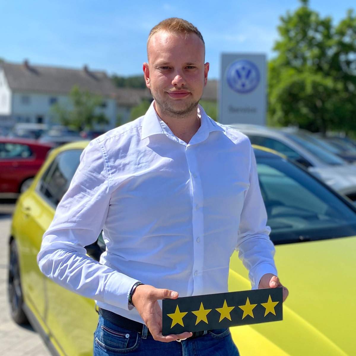 Verkäufer Jan Bruns lächelt in die Kamera und hält ein Schild mit fünf Sternen in der Hand
