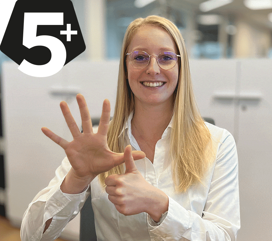 Mitarbeiterin zeigt mit ihrer Hand ein 5+ Zeichen