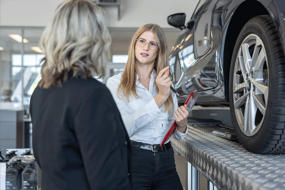 Serviceberaterin erklärt dem Kunden in der Dialogannahme etwas an seinem Auto.