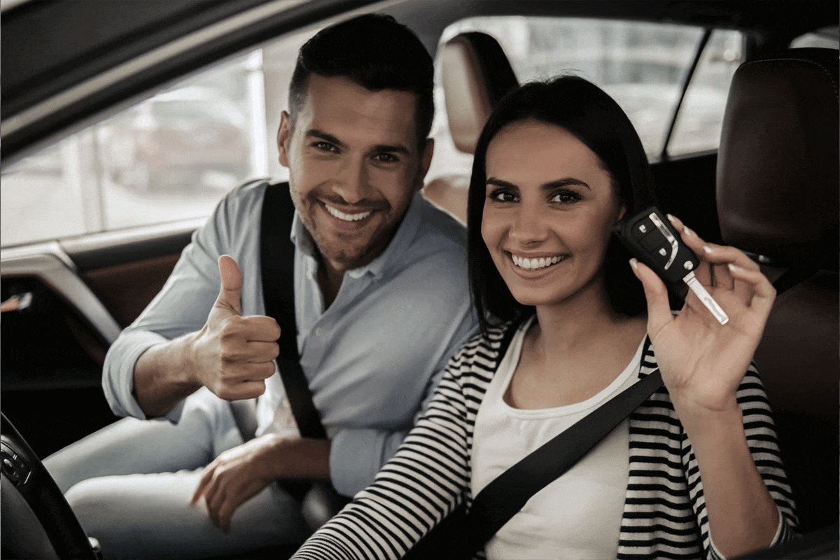 Zwei Kunden sitzen in einem Auto mit einem Schlüssel in der Hand.