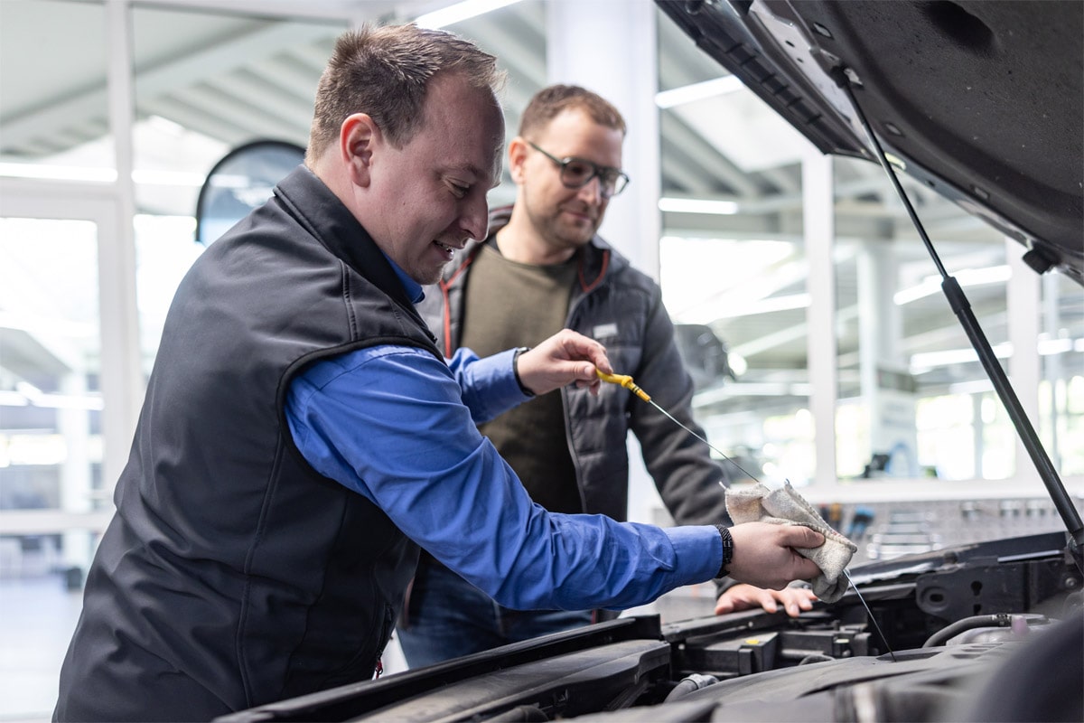 Serviceberater prüft gemeinsam mit dem Kunden den Ölstand in der Direktannahme.